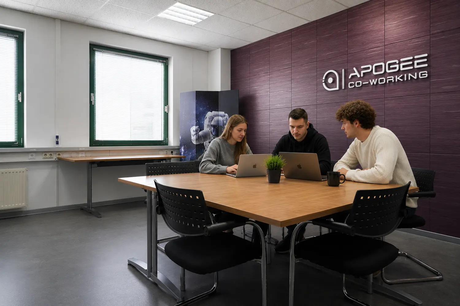 Drei Personen arbeiten gemeinsam an einem Tisch im Coworking-Bereich